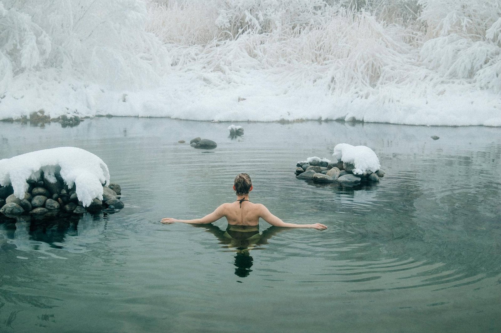 back of a young woman bathing in a winter lake